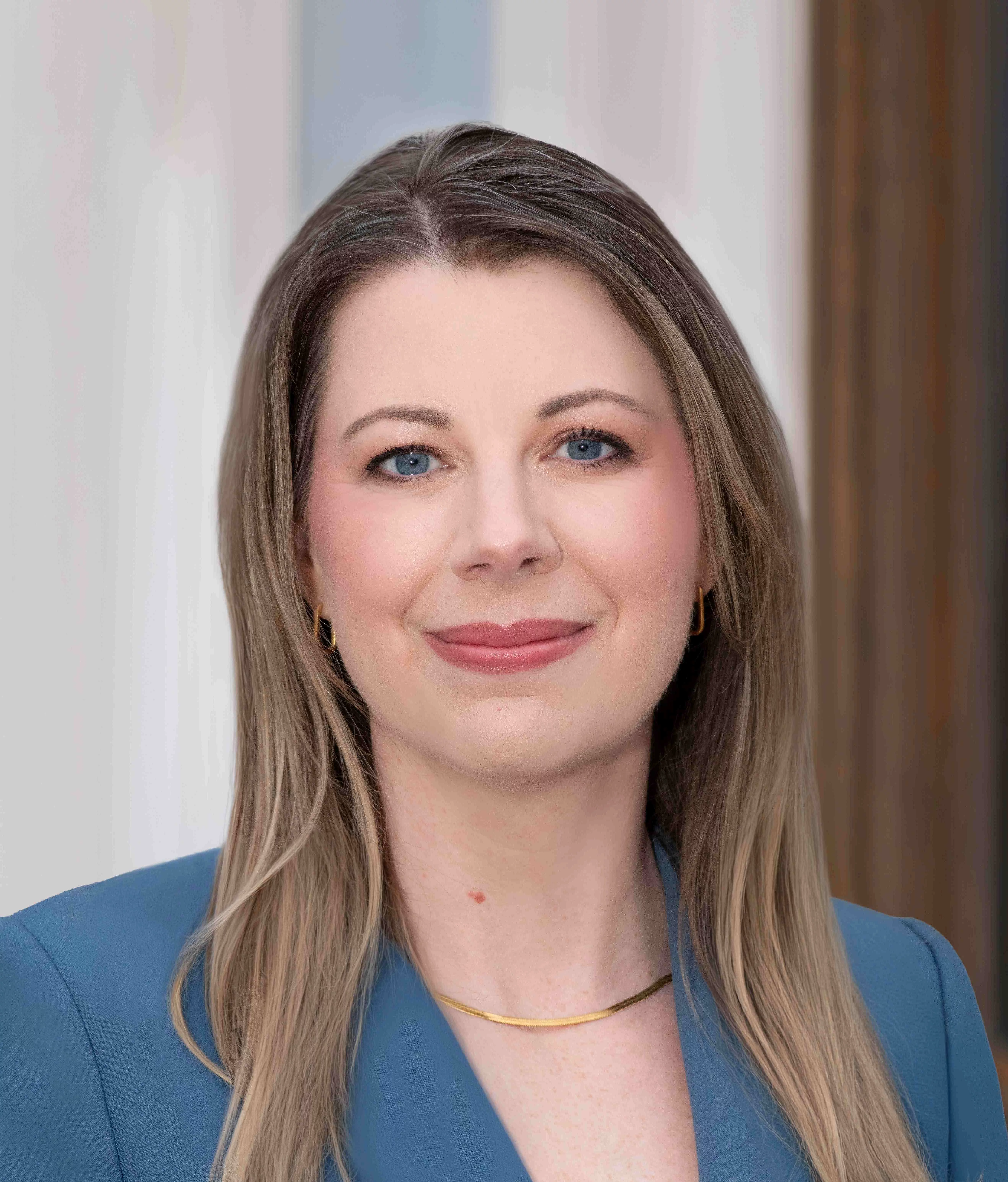 woman dressed in a blue suit with long light brown hair smiling